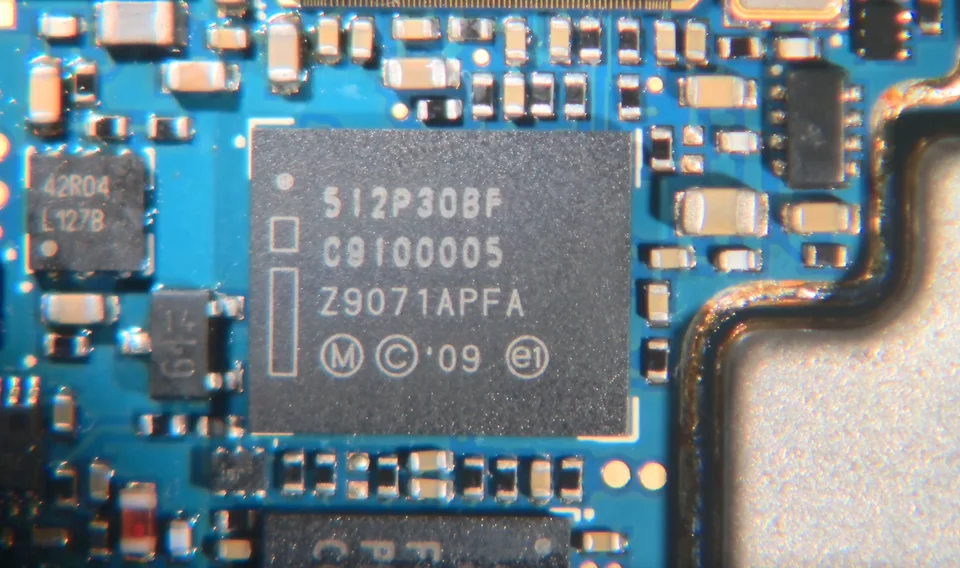 Microscope view of an APX4000 flash-memory chip mounted on a blue circuit board.
