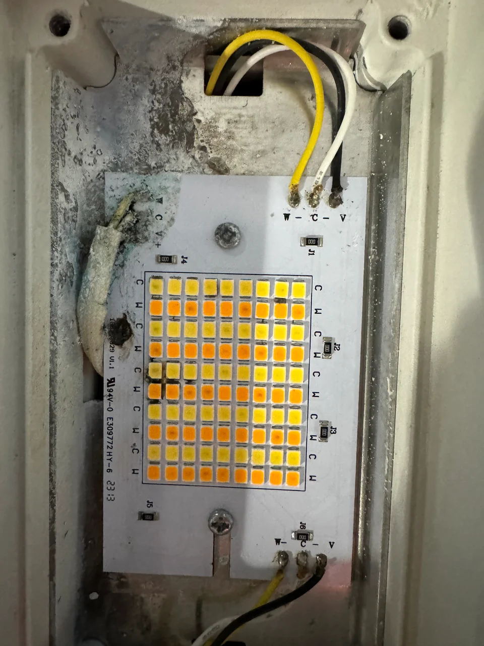 An outdoor LED light board with corrosion around the wiring and metal housing.